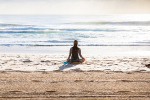 woman sitting on beach meditating